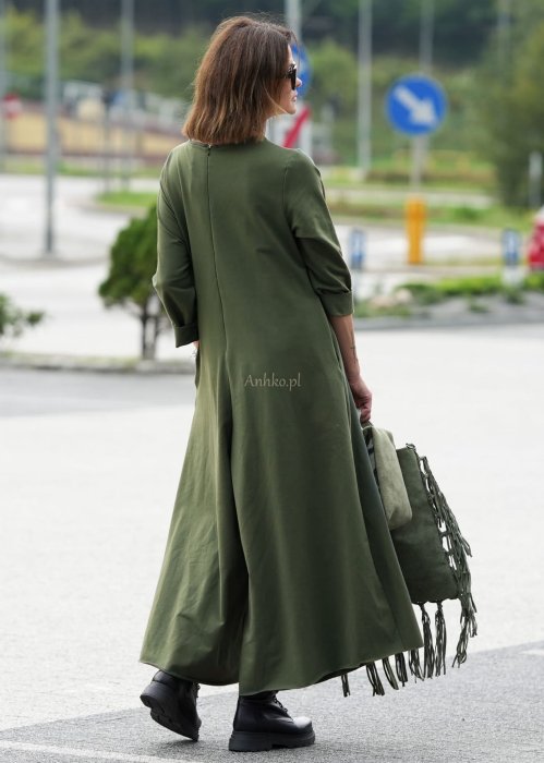 Damski kombinezon khaki z szeroką nogawką i długim rękawem, o luźnym kroju, stylizowany z czarnymi botkami i torebką w miejskiej scenerii.