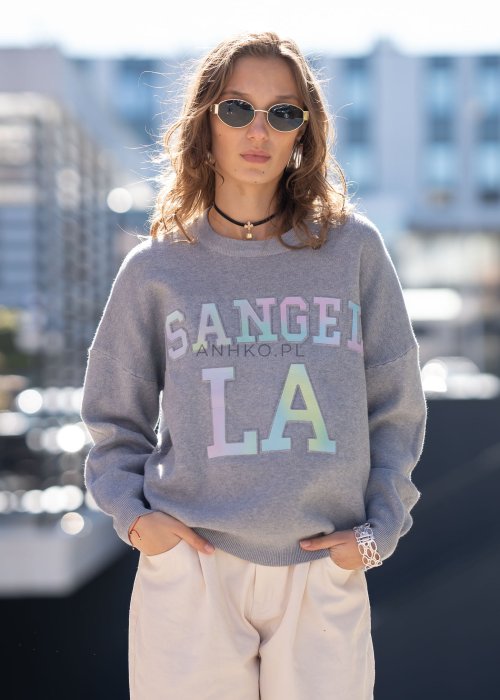 Szary sweter oversize z kolorowym napisem „Los Angeles” w pastelowych odcieniach. Miękki dzianinowy materiał, luźny fason i obniżona linia ramion nadają całości casualowego charakteru, idealnego do codziennych i streetwearowych stylizacji.