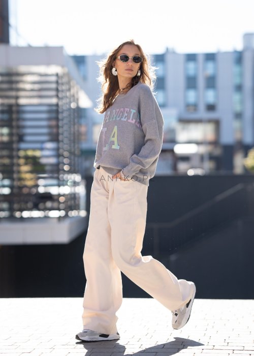 Szary sweter oversize z kolorowym napisem „Los Angeles” w pastelowych odcieniach. Miękki dzianinowy materiał, luźny fason i obniżona linia ramion nadają całości casualowego charakteru, idealnego do codziennych i streetwearowych stylizacji.