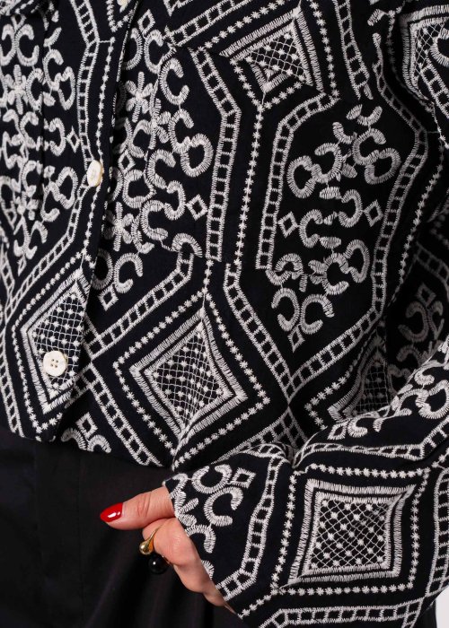 Czarno-biała koszula damska z efektownym haftowanym wzorem inspirowanym stylem boho i etnicznymi ornamentami. Luźny fason z szerokimi rękawami oraz kontrastowe zdobienia nadają modelowi wyjątkowego charakteru.