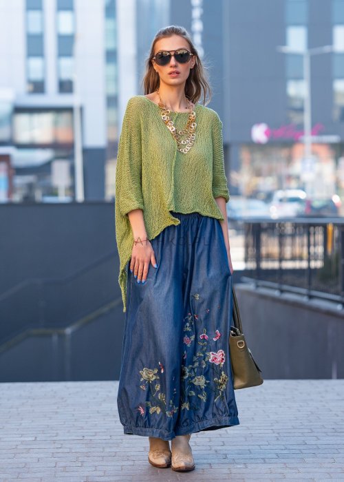 Granatowe jeansowe kuloty damskie z kwiatowym haftem przy dole nogawek, szeroka nogawka ze ściągaczem, stylizacja z zielonym swetrem.