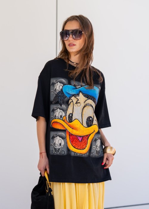 Czarny T-shirt oversize z dużym nadrukiem Kaczora Donalda w niebieskiej czapce, ozdobionym błyszczącymi cekinami. Luźny fason z krótkim rękawem tworzy modną, casualową stylizację i przyciąga uwagę wyrazistym motywem pop-art.