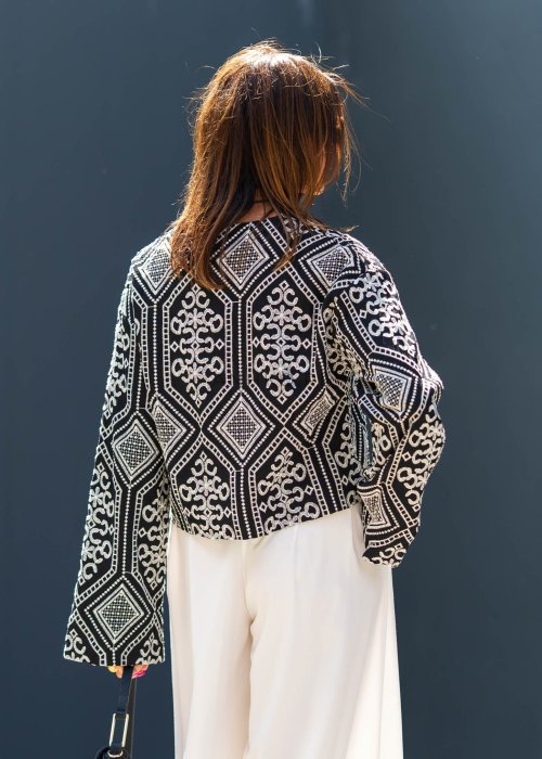 Czarno-biała koszula damska z efektownym haftowanym wzorem inspirowanym stylem boho i etnicznymi ornamentami. Luźny fason z szerokimi rękawami oraz kontrastowe zdobienia nadają modelowi wyjątkowego charakteru.