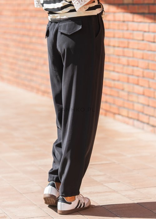 Czarne damskie spodnie z lekkiego materiału, o luźnym kroju z elastyczną talią i ściągaczami przy nogawkach w stylu casual