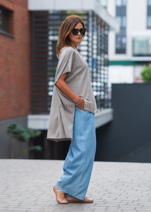 Bluzka oversize taupe z asymetrycznym dołem i wydłużonym tyłem, zestawiona z jasnymi jeansami. Luźny fason tworzy nowoczesną, minimalistyczną stylizację.