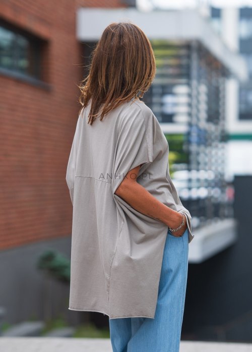 Bluzka oversize taupe z asymetrycznym dołem i wydłużonym tyłem, zestawiona z jasnymi jeansami. Luźny fason tworzy nowoczesną, minimalistyczną stylizację.