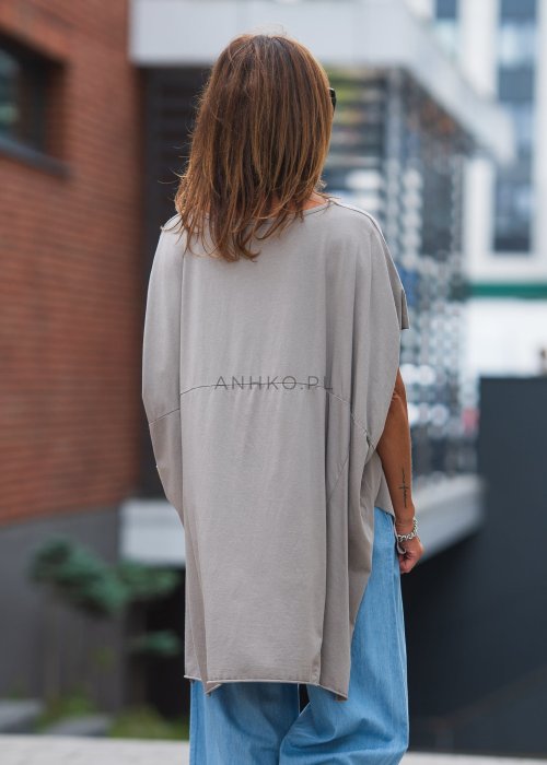 Bluzka oversize taupe z asymetrycznym dołem i wydłużonym tyłem, zestawiona z jasnymi jeansami. Luźny fason tworzy nowoczesną, minimalistyczną stylizację.