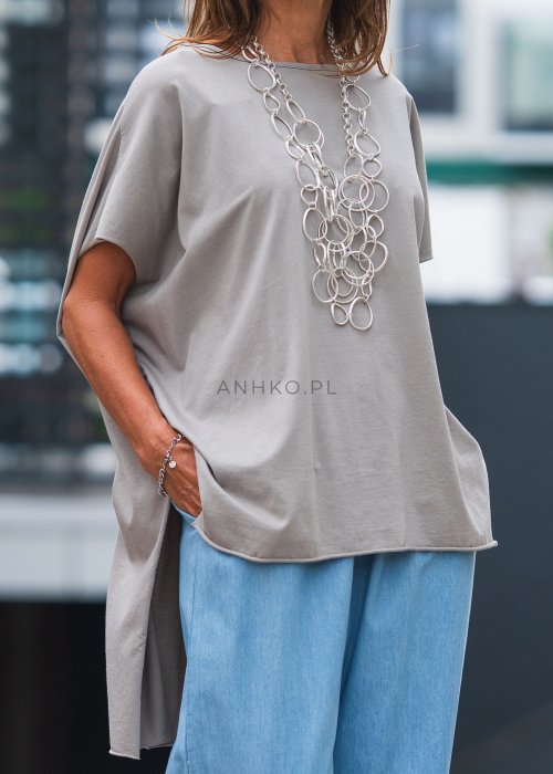 Bluzka oversize taupe z asymetrycznym dołem i wydłużonym tyłem, zestawiona z jasnymi jeansami. Luźny fason tworzy nowoczesną, minimalistyczną stylizację.