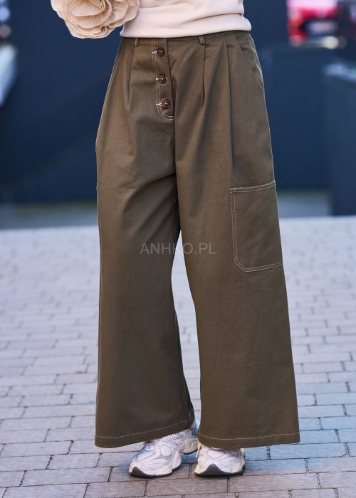 Luźne, szerokie spodnie w kolorze khaki o casualowym charakterze. Model z wysokim stanem, zapinany na duże, ozdobne guziki przesunięte lekko na bok, co nadaje im oryginalności.