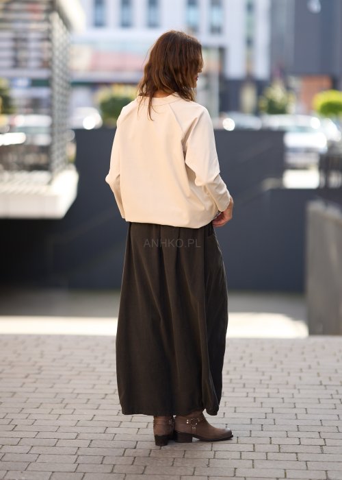 Brązowa spódnica maxi z elastyczną talią i kieszeniami, o luźnym kroju, zestawiona z beżową bluzką i brązowymi botkami w eleganckiej, miejskiej stylizacji.