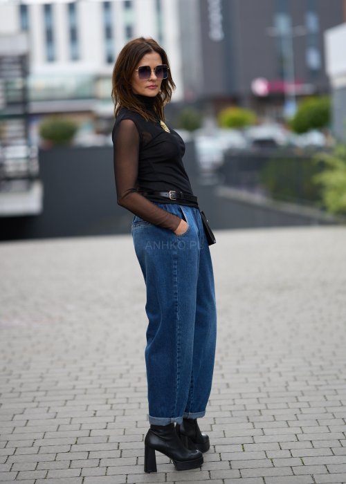 Niebieskie jeansy damskie o kroju slouchy z elastycznym pasem i podwiniętą nogawką. Stylizacja z botkami na obcasie w miejskim, casualowym stylu.