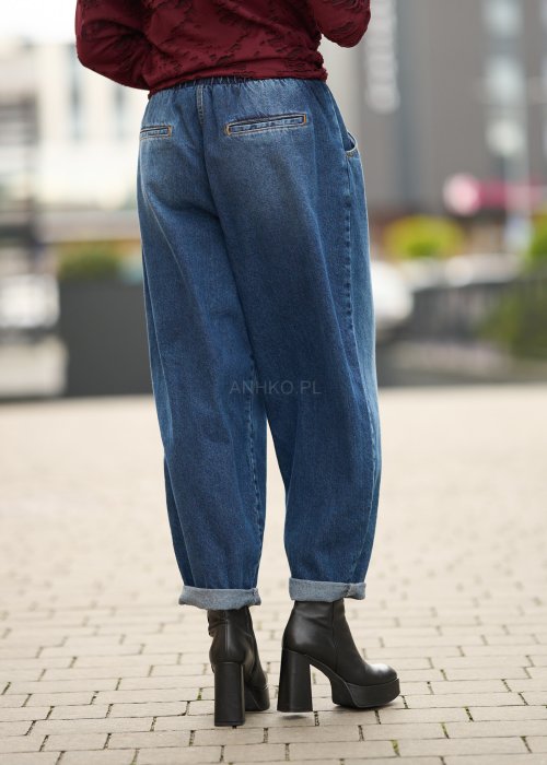 Niebieskie jeansy damskie o kroju slouchy z elastycznym pasem i podwiniętą nogawką. Stylizacja z botkami na obcasie w miejskim, casualowym stylu.