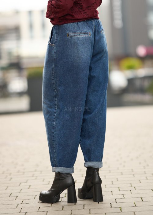 Niebieskie jeansy damskie o kroju slouchy z elastycznym pasem i podwiniętą nogawką. Stylizacja z botkami na obcasie w miejskim, casualowym stylu.