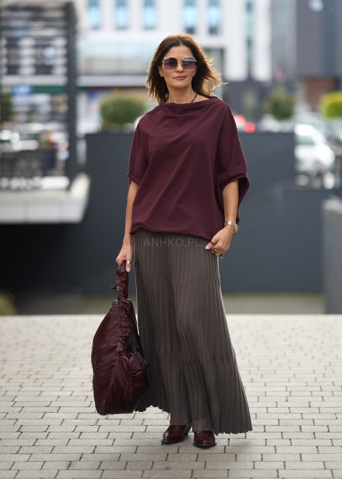 Śliwkowa bluzka damska oversize z rękawami typu nietoperz i szerokim dekoltem, zestawiona ze spódnicą w eleganckiej miejskiej stylizacji.