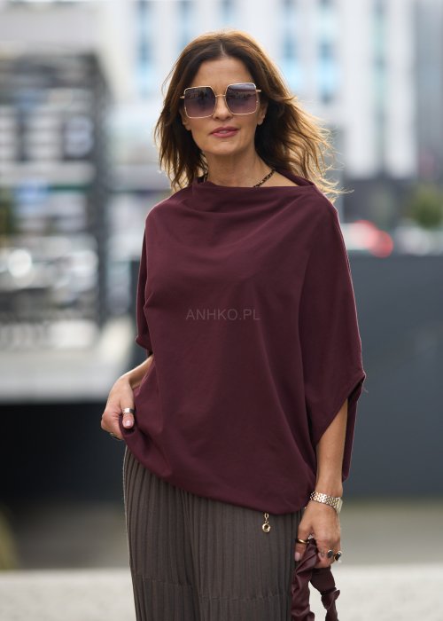 Śliwkowa bluzka damska oversize z rękawami typu nietoperz i szerokim dekoltem, zestawiona ze spódnicą w eleganckiej miejskiej stylizacji.
