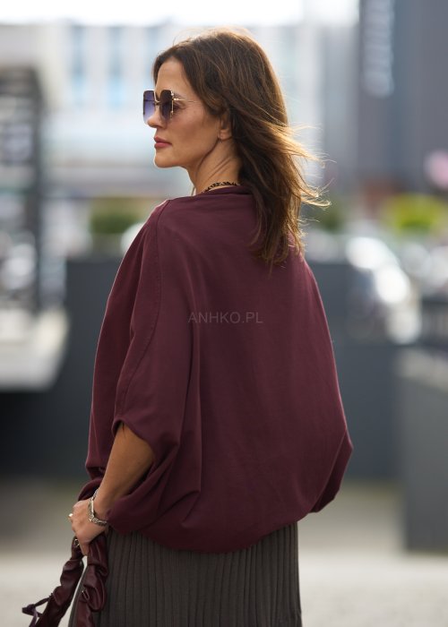Śliwkowa bluzka damska oversize z rękawami typu nietoperz i szerokim dekoltem, zestawiona ze spódnicą w eleganckiej miejskiej stylizacji.