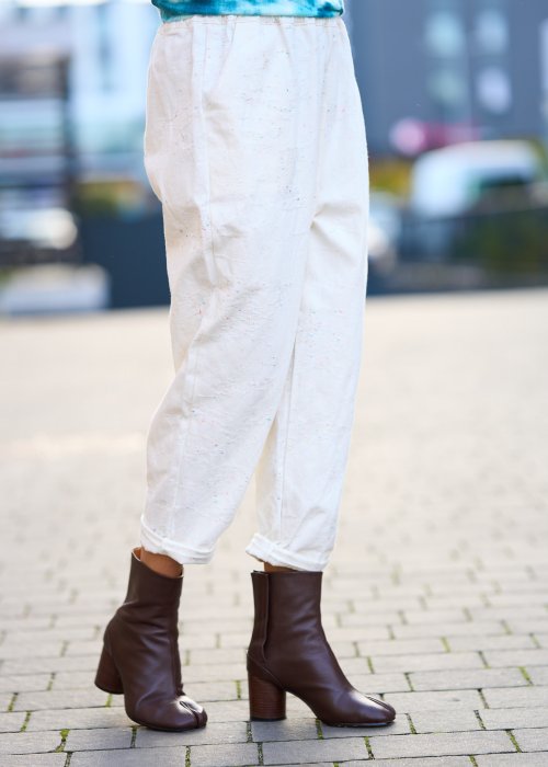 Kremowe spodnie z naturalnej tkaniny, luźna nogawka, elastyczny pas i swobodny fason w stylu boho