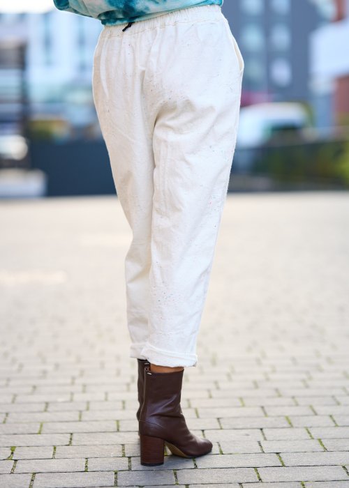 Kremowe spodnie z naturalnej tkaniny, luźna nogawka, elastyczny pas i swobodny fason w stylu boho