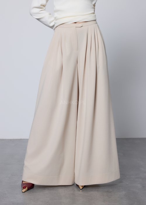 Beżowe spodnie damskie wide leg z wysokim stanem i szerokimi nogawkami, elegancki, lejący fason w nowoczesnej stylizacji.