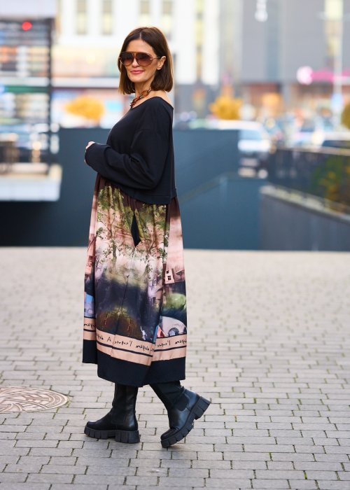 Czarna sukienka midi z długim rękawem i artystycznym printem na dole, stylizacja z botkami i jasną torebką.