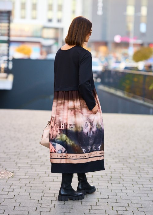 Czarna sukienka midi z długim rękawem i artystycznym printem na dole, stylizacja z botkami i jasną torebką.