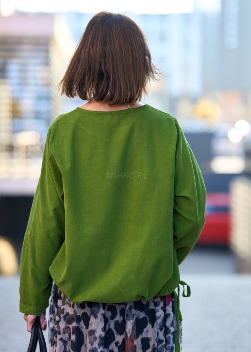 Zielona bluzka oversize z długim rękawem i regulowanym dołem, stylizowana z printowaną spódnicą maxi i botkami w miejskim looku.