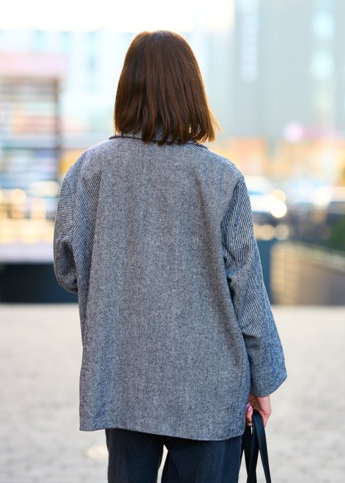 Szara marynarka damska w drobną jodełkę o kroju oversize z ozdobnymi naszywkami, stylizacja z czarnym topem i szerokimi spodniami.