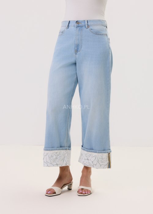 Jasnoniebieskie damskie jeansy Blue Blossom Roll z prostą, lekko skróconą nogawką i wywiniętym mankietem. Model z klasycznymi kieszeniami oraz dekoracyjnym, jasnym wzorem kwiatowym na podwinięciach i tylnych kieszeniach