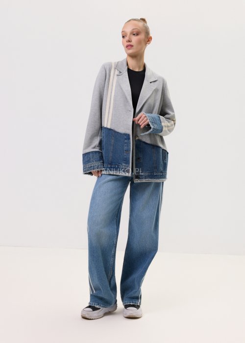 Szara marynarka Stron Denim z jeansowymi wstawkami i surowym wykończeniem, zapinana na guziki, zestawiona z jasnymi jeansami w casualowej stylizacji.
