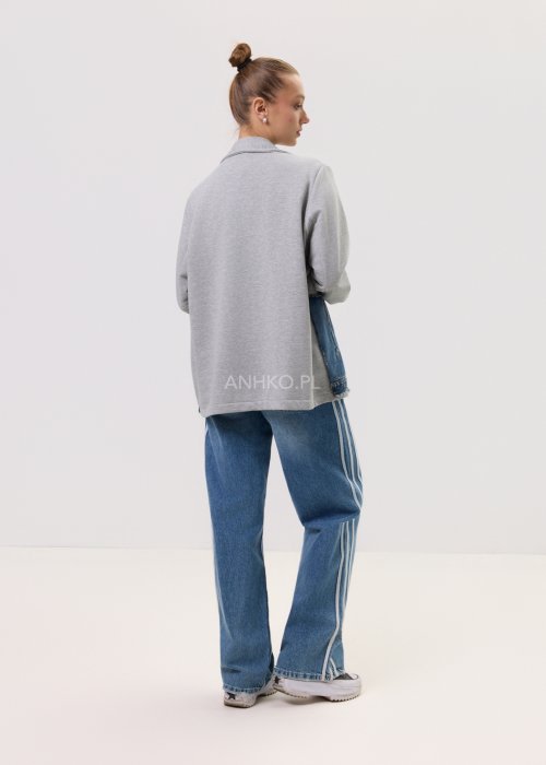 Szara marynarka Stron Denim z jeansowymi wstawkami i surowym wykończeniem, zapinana na guziki, zestawiona z jasnymi jeansami w casualowej stylizacji.