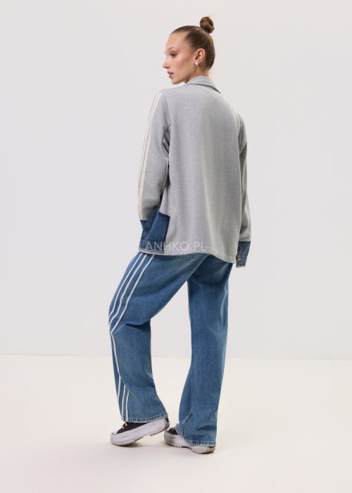 Szara marynarka Stron Denim z jeansowymi wstawkami i surowym wykończeniem, zapinana na guziki, zestawiona z jasnymi jeansami w casualowej stylizacji.