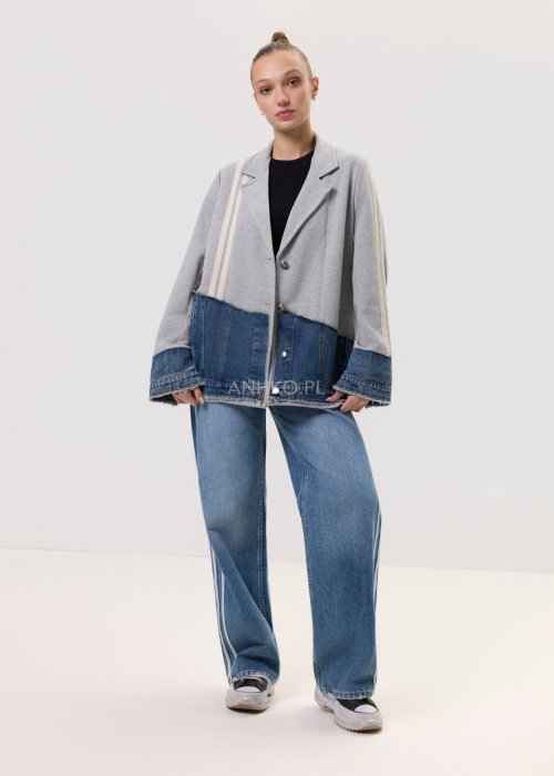 Szara marynarka Stron Denim z jeansowymi wstawkami i surowym wykończeniem, zapinana na guziki, zestawiona z jasnymi jeansami w casualowej stylizacji.
