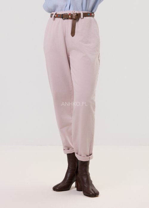 Pudrowe spodnie damskie chino o zwężanym kroju z podwijaną nogawką i paskiem, styl elegancki casual.