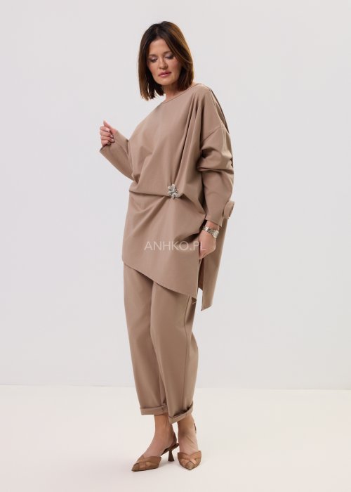 Spodnie Starola Rose Cappuccino w odcieniu ciepłego beżu, z podwiniętą nogawką i eleganckim paskiem, w minimalistycznej stylizacji z butami na obcasie.
