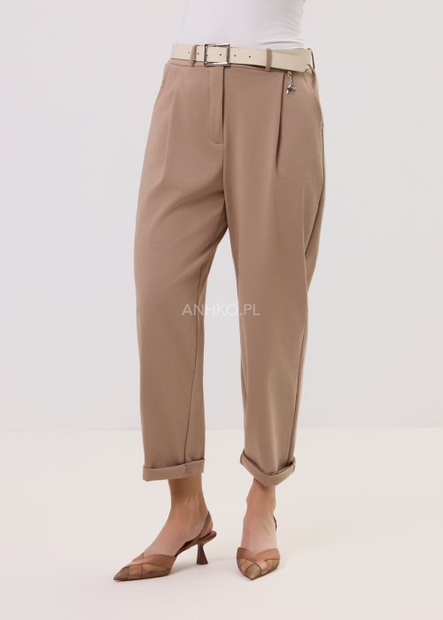 Spodnie Starola Rose Cappuccino w odcieniu ciepłego beżu, z podwiniętą nogawką i eleganckim paskiem, w minimalistycznej stylizacji z butami na obcasie.