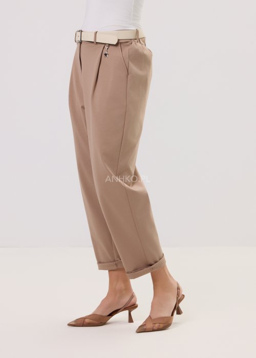 Spodnie Starola Rose Cappuccino w odcieniu ciepłego beżu, z podwiniętą nogawką i eleganckim paskiem, w minimalistycznej stylizacji z butami na obcasie.
