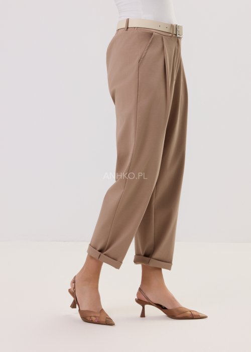 Spodnie Starola Rose Cappuccino w odcieniu ciepłego beżu, z podwiniętą nogawką i eleganckim paskiem, w minimalistycznej stylizacji z butami na obcasie.