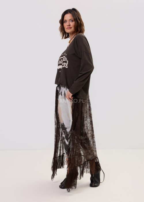 Brązowa bluzka oversize z długim rękawem i dekoltem V, z nadrukiem „California 79”, zestawiona z jeansami tie-dye i koronkową narzutką w stylizacji casua