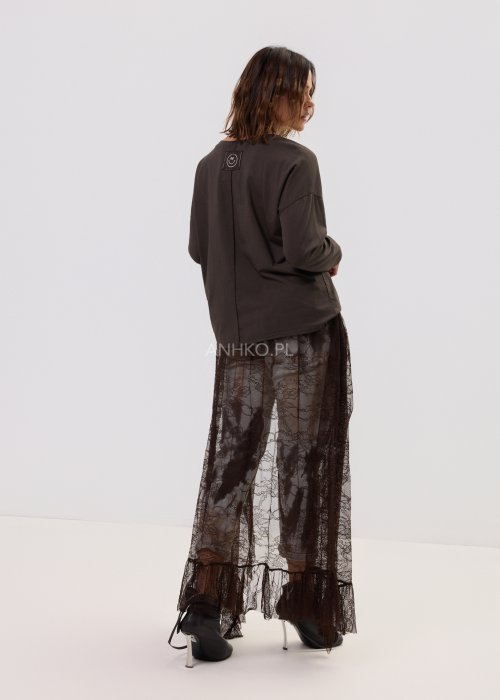 Brązowa bluzka oversize z długim rękawem i dekoltem V, z nadrukiem „California 79”, zestawiona z jeansami tie-dye i koronkową narzutką w stylizacji casua