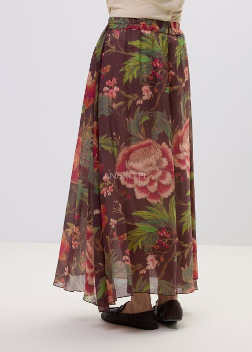 Zwiewna spódnica maxi w kwiatowy wzór na ciemnym tle z dekoracyjnym paskiem i kwiatową aplikacją. Lekka, elegancka spódnica damska z romantycznym printem, idealna do stylizacji boho i casual chic.