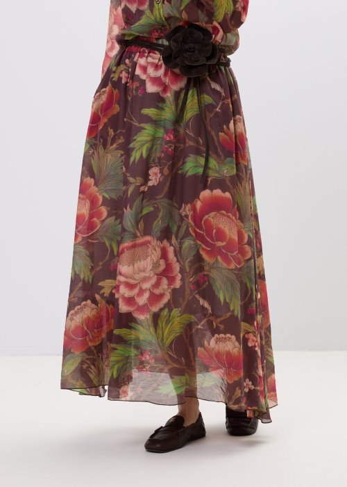 Zwiewna spódnica maxi w kwiatowy wzór na ciemnym tle z dekoracyjnym paskiem i kwiatową aplikacją. Lekka, elegancka spódnica damska z romantycznym printem, idealna do stylizacji boho i casual chic.