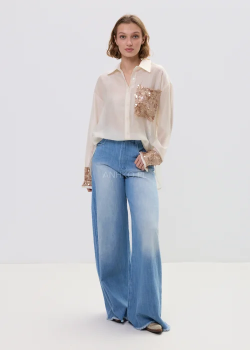 Beżowa koszula damska z cekinową kieszenią i mankietami, luźny fason, lekko transparentny materiał, styl casual-elegant.