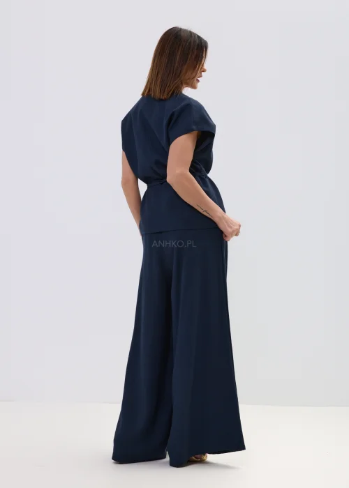 Granatowe spodnie z dodatkiem lnu o szerokiej nogawce, lekkie i zwiewne z wysokim stanem, elegancka stylizacja z sandałami.