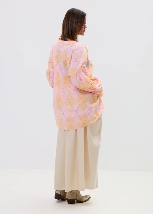 Koszula oversize w pastelową kratę w odcieniach różu i pomarańczu, z bufiastymi rękawami i wiązaniem z przodu, stylizowana z długą beżową spódnicą w kobiecym, lekkim looku.