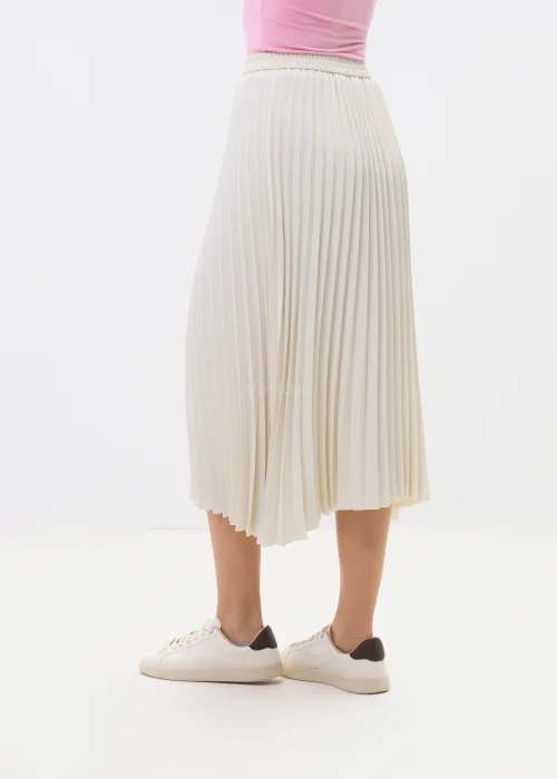 Kremowa spódnica plisowana midi z elastyczną talią, o lekkim i zwiewnym fasonie, zestawiona ze sneakersami w minimalistycznej stylizacji.