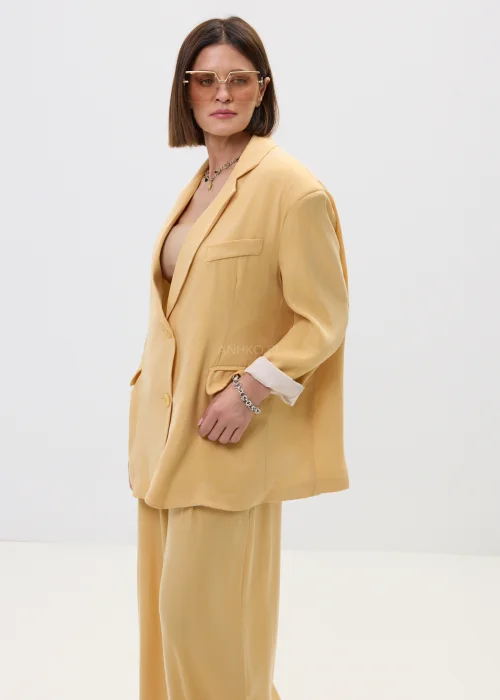 Marynarka damska w masełkowym odcieniu, o luźnym kroju z klapami, zapinana na guziki, z kieszeniami – elegancki styl w nowoczesnym, lekkim wydaniu.