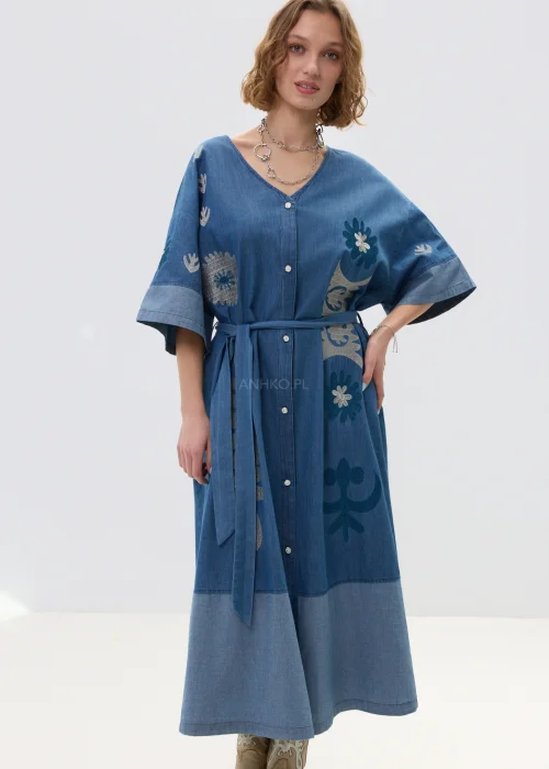 Jeansowa sukienka maxi w odcieniu niebieskiego denimu z haftowanymi wzorami, wiązana w talii paskiem, zapinana na guziki, o luźnym fasonie z szerokimi rękawami, stylizowana z kowbojkami.