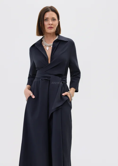Granatowa sukienka midi o kopertowym kroju z wiązaniem w talii i rękawem 3/4, zestawiona z wysokimi czarnymi kozakami w eleganckiej stylizacji.