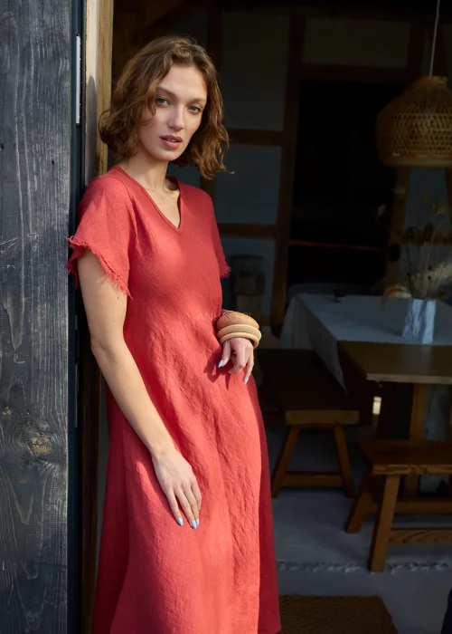 Czerwona lniana sukienka midi o luźnym kroju z krótkim rękawem i surowym wykończeniem, lekko rozkloszowany fason, styl casual z kowbojkami.