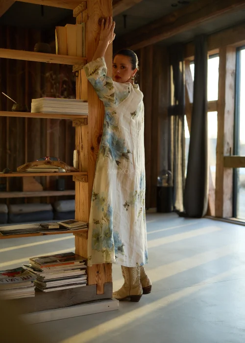 Lniana sukienka koszulowa maxi w beżowym kolorze z delikatnym kwiatowym wzorem, o luźnym kroju z krótkim rękawem i zapięciem na guziki, stylizacja w naturalnym, eleganckim klimacie.